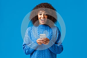 Excited and overwhelmed smiling attractive young african-american woman, wearing winter blue sweater, looking amazed and