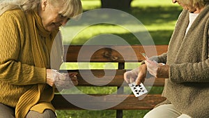 Excited pensioners playing cards in park, happy time together, secure old age