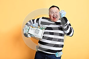 Excited plump man in striped uniform rejoicing at stolen money