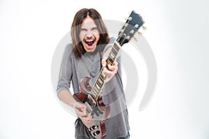 Excited popular young male singer shouting and playing electric guitar