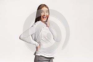 Excited Pregnant Woman Touching Chin Smiling At Camera, Studio Shot