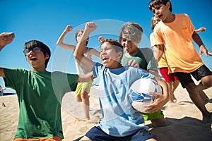 Excited preteen boys cheering after game on beach