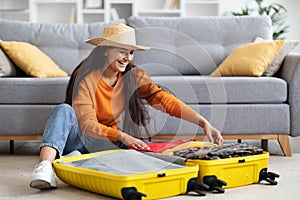 Excited pretty hindu woman packing suitcase at home