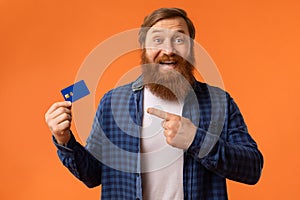 Excited Redhaired Bearded Guy Showing Credit Card Over Orange Background