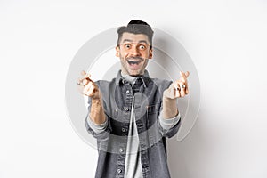 Excited romantic man showing hand hearts and smiling at camera, express love and affection, standing on white background