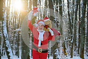 Excited Santa in the winter field. Santa Claus on Christmas Eve is carrying presents to children in a bag.