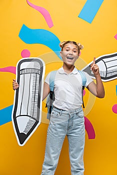 Excited schoolgirl having idea while holding