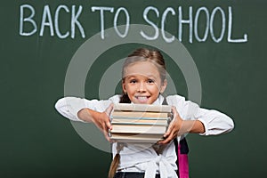 Excited schoolgirl holding stack of books