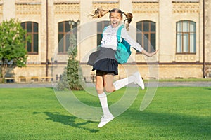 Excited schoolgirl jumping midair, school. Energetic teenage girl carrying school bag. Back to school