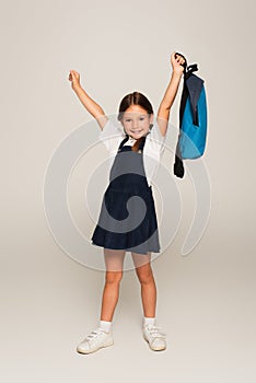 excited schoolkid with blue backpack showing photo