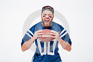 Excited screaming man fan in blue t-shirt holding rugby ball.