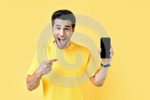 Excited screaming man pointing his finger showing mobile phone and looking to camera