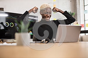 Excited screaming young african business man or entrepreneur working with laptop computer