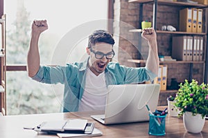 Excited screaming young man looking at the screen of his compute