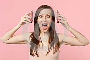 Excited screaming young woman holding halfs of fresh ripe pitahaya, dragon fruit isolated on pink pastel wall background