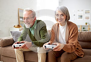 Excited senior couple playing video console games at home