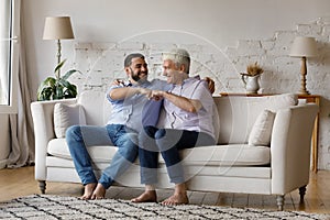 Excited senior father and adult grownup son giving fist bump