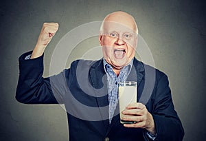 Excited senior gentleman holding a glass of milk