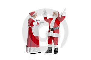 Excited senior man and beautiful woman, Santa Claus and missis Claus in traditional New Year costume isolated on white