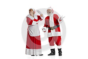 Excited senior man and beautiful woman, Santa Claus and missis Claus in traditional New Year costume isolated on white