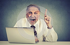 Excited senior man using laptop computer has an idea