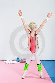 excited senior sportswoman raising hands and smiling