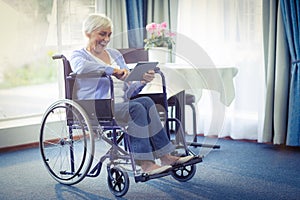 Excited senior woman on wheelchair using digital tablet