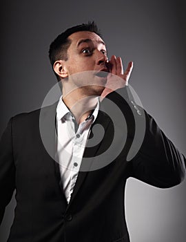 Excited shouting young business man gesturing the hands loudspeaker sign in celebrating emotion with wide open mouth to agitate on photo