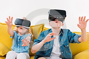 excited siblings using virtual reality headset and sitting