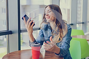 Excited smiling happy woman having a rest in a cafe, she is looking at screen of her smartphone telephone mobile phone sms notific