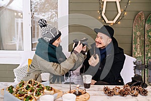 Excited smiling woman taking photo of a funny man with a pipe on digital camera