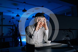 Excited stressed young man shouting with frustrated and furious working office at night on computer alone. Overworked