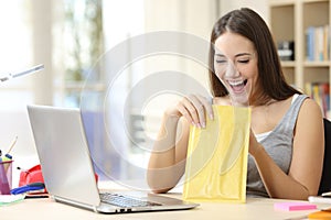 Excited student opening padded envelope at home