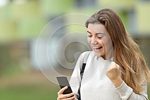 Excited student reading news on a smart phone