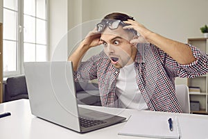 Excited stunned man with shocked expression reads email on laptop screen with favorable proposition.