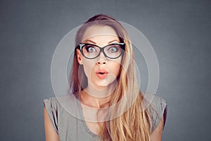 Excited stunned woman in eyeglasses isolated on the  grey background