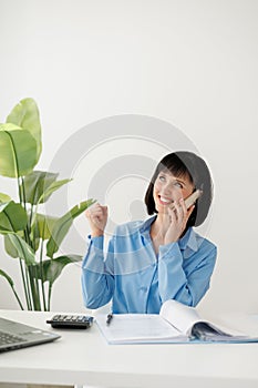 Excited successful employee businesswoman talking on smartphone say yes doing winner gesture, clench fist, sit at office