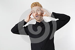 Excited surprised shock young man isolated on gray background. Happy Redhead guy with red beard in black stylish shirt. Success