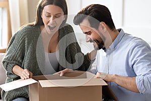 Excited surprised woman looking into cardboard box, receive parcel