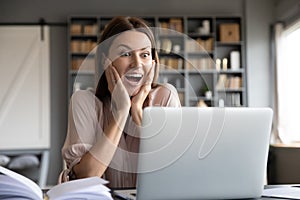 Excited surprised woman looking at laptop screen, reading news
