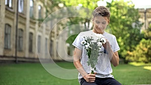 Excited teen boy with bouquet of flowers waiting for girlfriend, anticipation