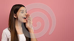 Excited teen girl with her hand near mouth shouting at copy space