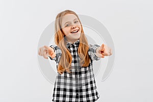 Excited teen girl wearing in casual shirt point index fingers camera on you motivating, standing over white background