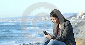 Excited teen reading good news on the beach