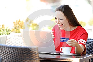 Excited teen in red finding online offers on laptop