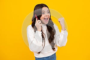 Excited teenager girl 12, 13, 14 years old with smart phone. Hipster teen girl types message on cellphone, enjoys mobile