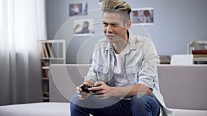 Excited teenager playing video games with joystick, leisure entertainment