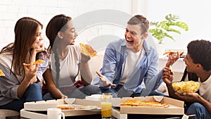 Excited teenagers eating pizza and talking at home
