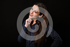 Excited thinking toothy smiling business woman with folded arms in blue shirt on black background with empty copy space for text.