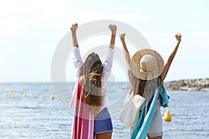 Excited tourists raising arms celebrating vacation on the beach